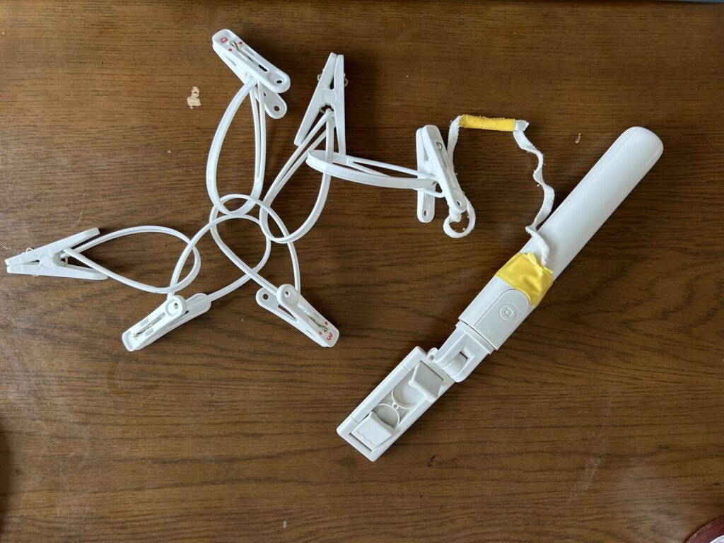 自撮り棒にゴム紐を付けて洗濯ばさみで延長してベッド脇にくくりつけている