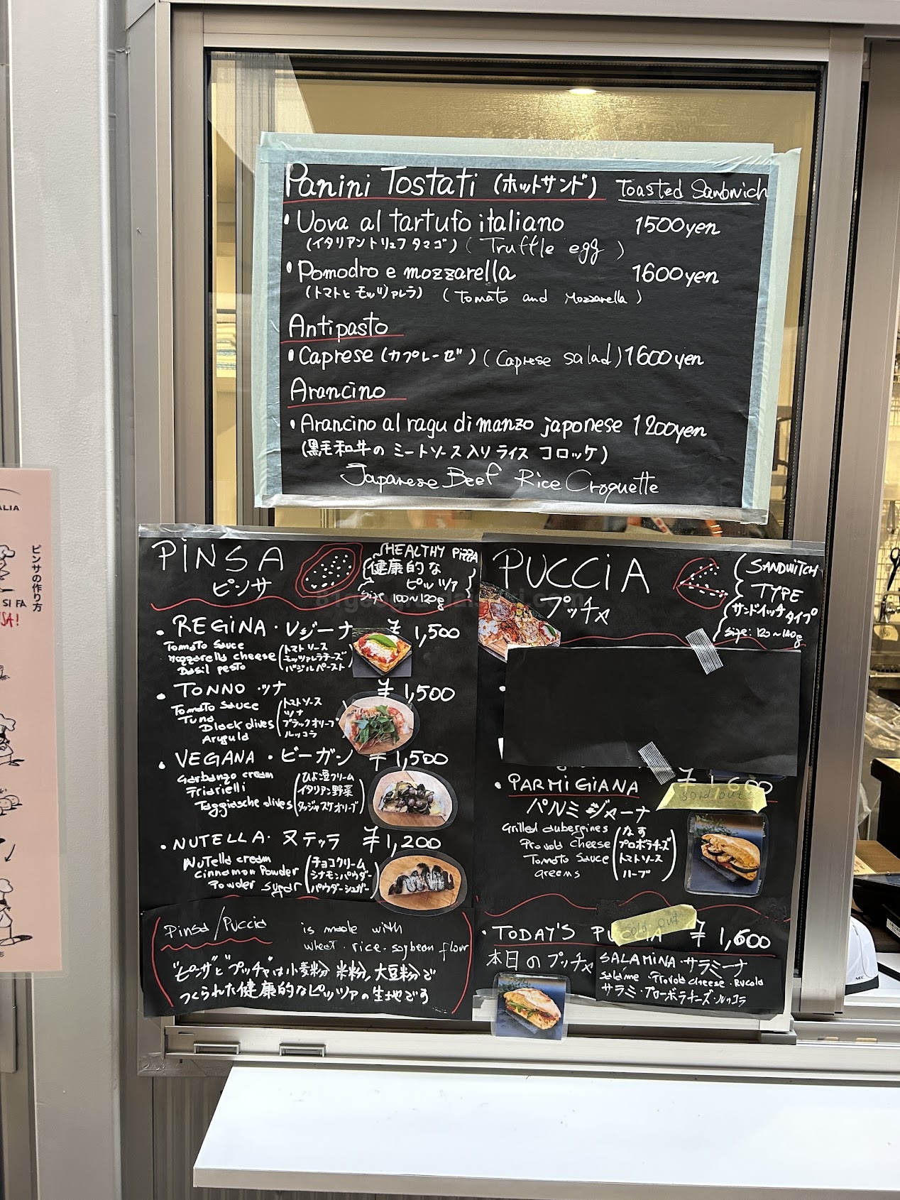 ピザのメニュー。ガラス窓の向こうで見えにくいです。
